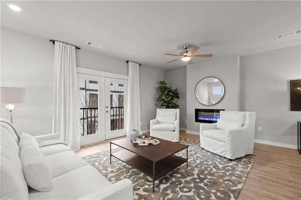 Living room featuring french doors, light wood finished floors, a glass covered fireplace, and a ceiling fan