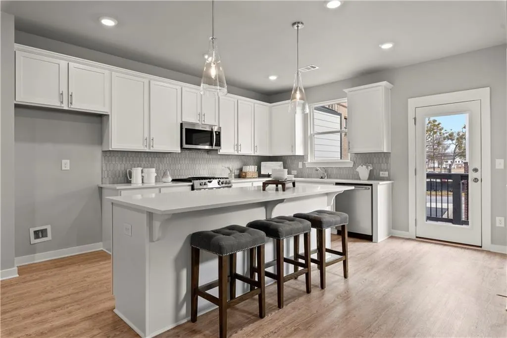 Kitchen with a kitchen bar, backsplash, hanging light fixtures, a kitchen island, and appliances with stainless steel finishes