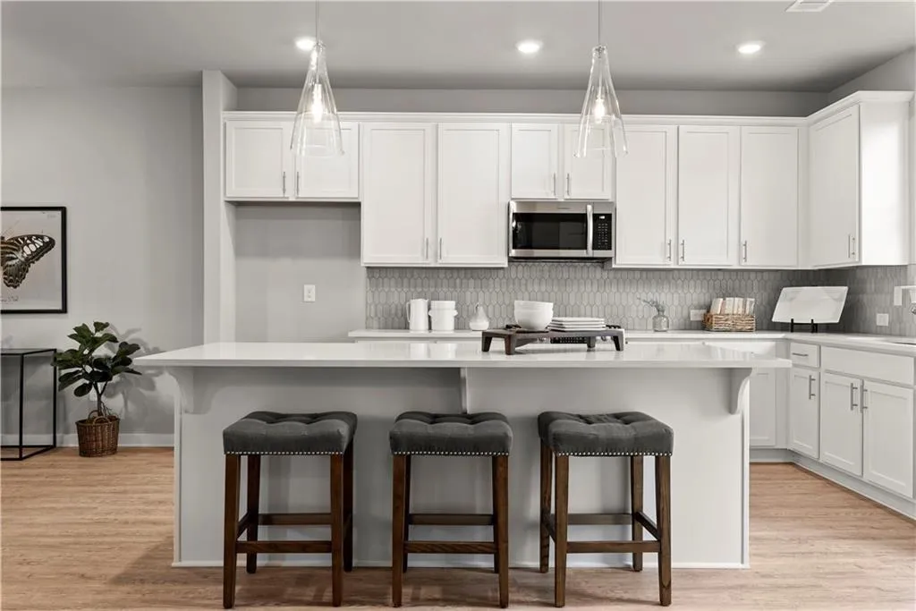 Kitchen featuring a kitchen breakfast bar, white cabinets, light wood-style flooring, and recessed lighting