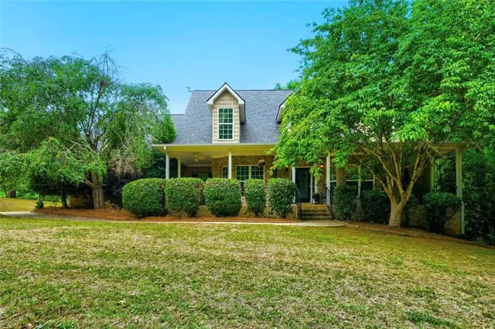 Traditional-style home featuring a covered front porch, dormer window, and brick facade details
