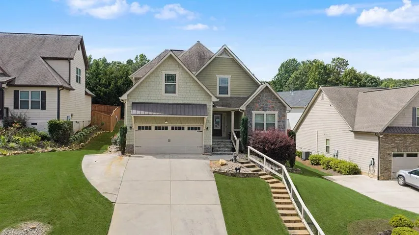 Craftsman-style home featuring a two-car garage, stone and shake siding accents, a front porch with steps, and a concrete driveway