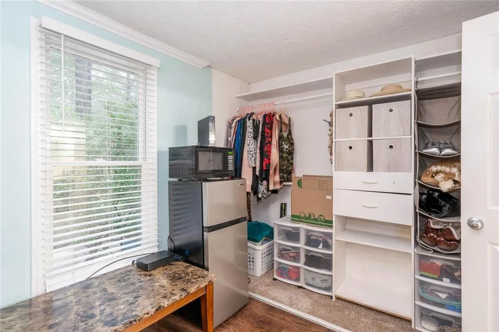 Walk in closet with dark wood-type flooring