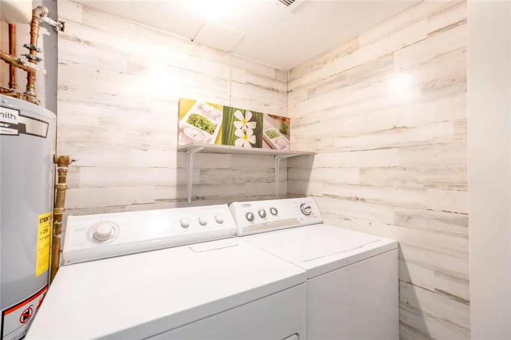 Laundry area featuring gas water heater, faux wooden walls, and washing machine and dryer