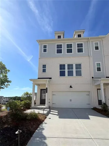 Three-story townhome featuring a light brick facade and gray siding accents