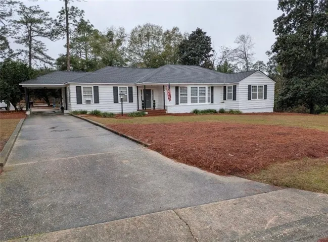 Ranch-style house featuring a carport, driveway, and a front yard