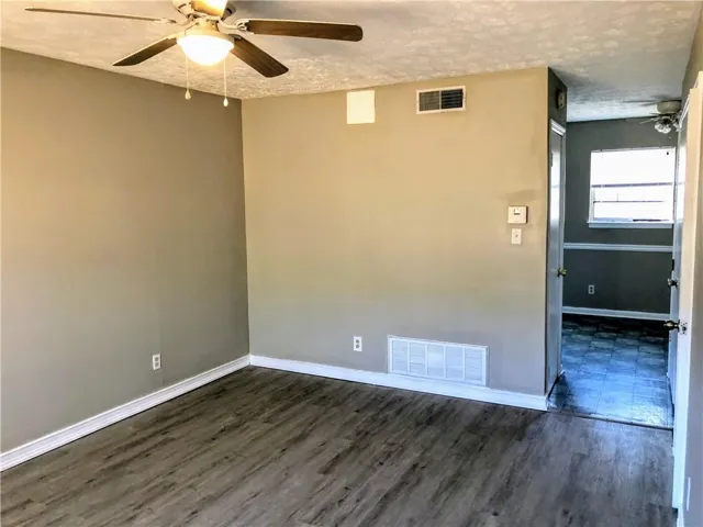 Neutral-toned interior featuring wood-finish flooring, white baseboards, and a ceiling fan with integrated lighting