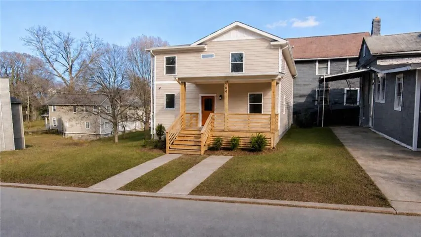 Two-story residence featuring light-toned siding and a prominent covered front porch with natural wood railings