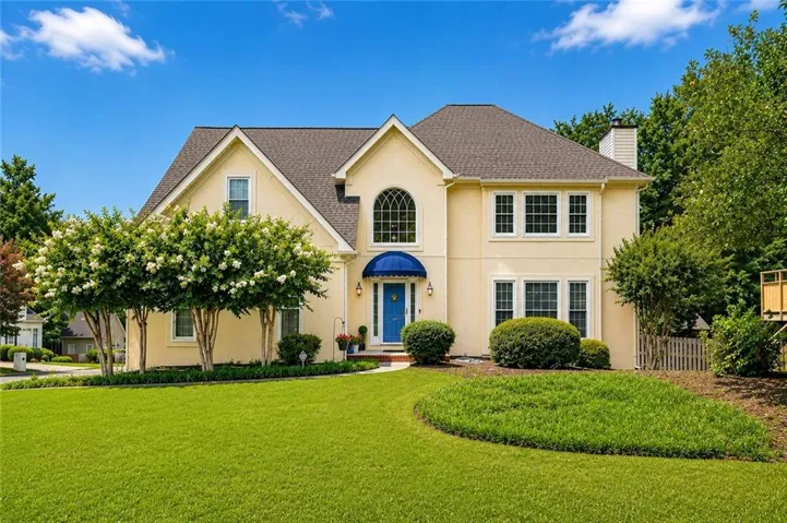 Stucco-finish exterior with a dark shingle roof and a prominent arched window