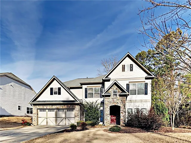 View of front of property featuring stone siding, concrete driveway, and an attached garage