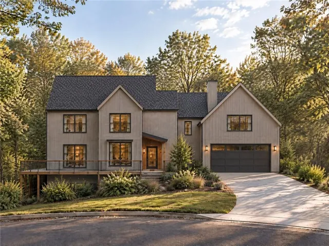 Modern farmhouse-style residence with dark trim windows, covered entry, attached two-car garage, and a spacious deck