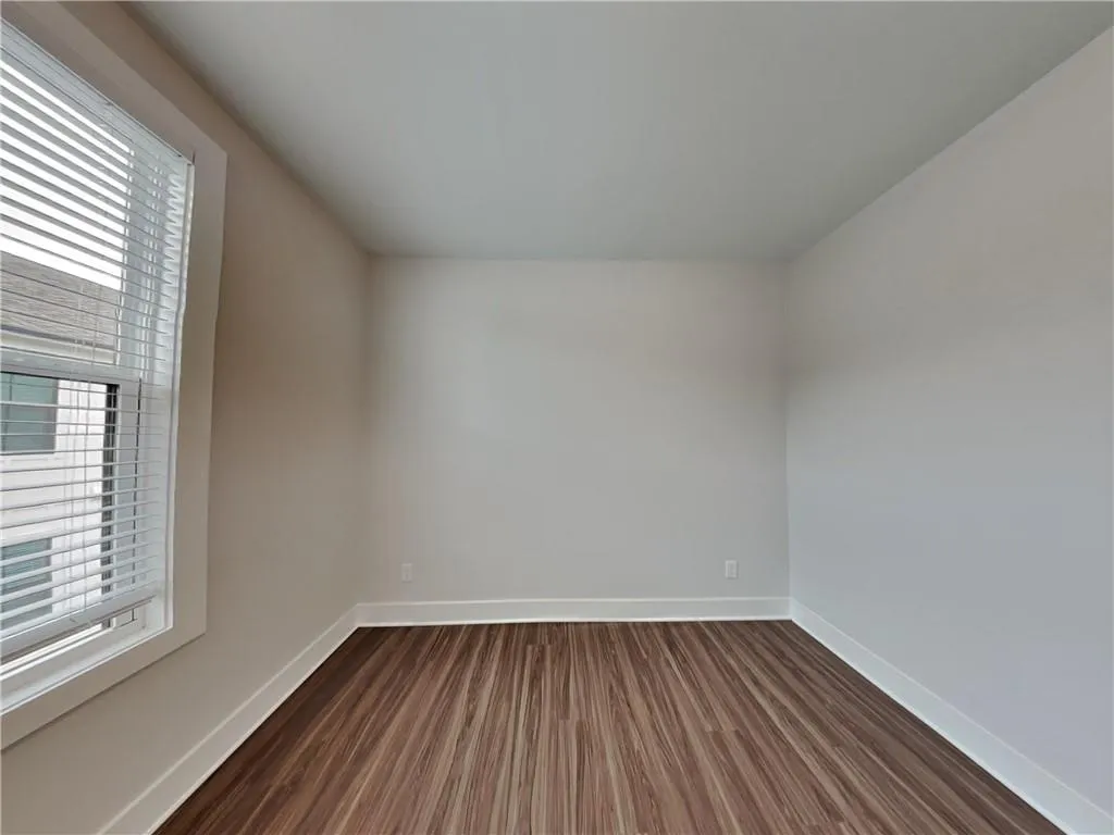 Unfurnished room with dark wood-style floors and baseboards
