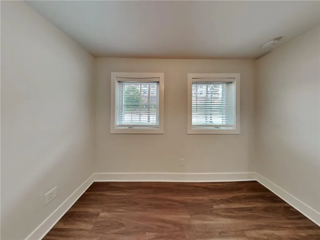 Unfurnished room with dark wood-style floors and baseboards