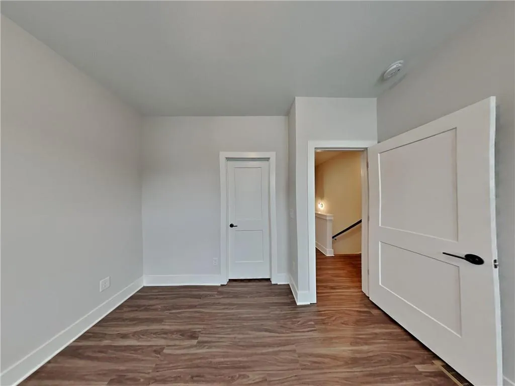 Unfurnished bedroom with dark wood-type flooring and baseboards