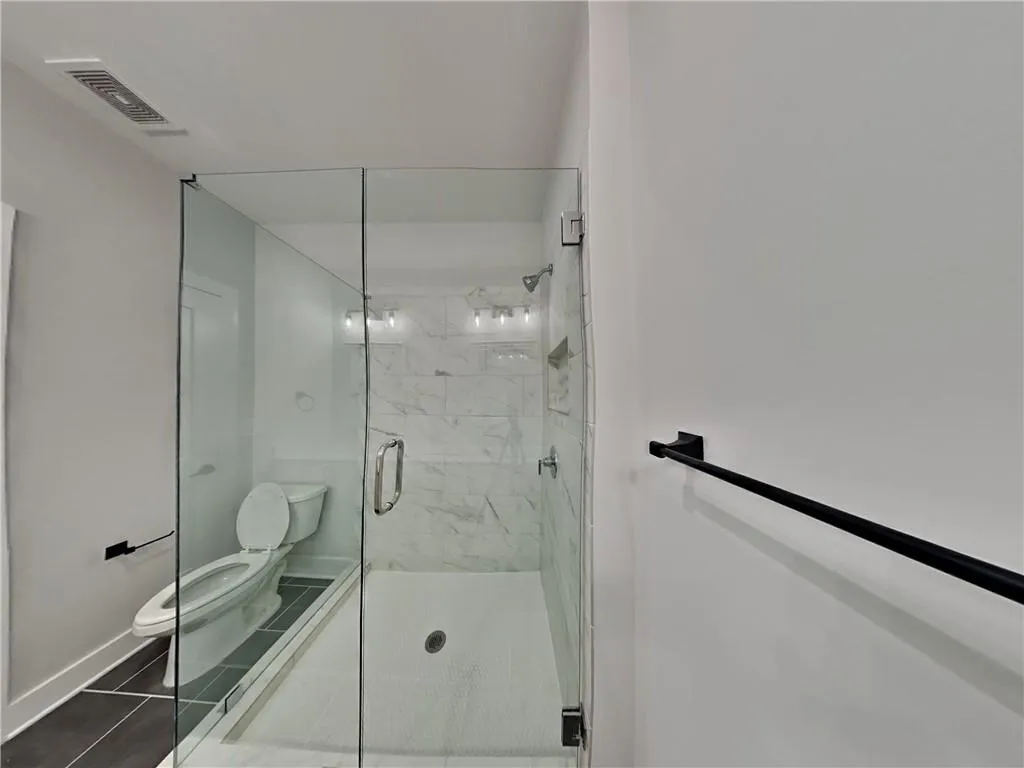 Full bath featuring a marble finish shower and dark tile patterned flooring