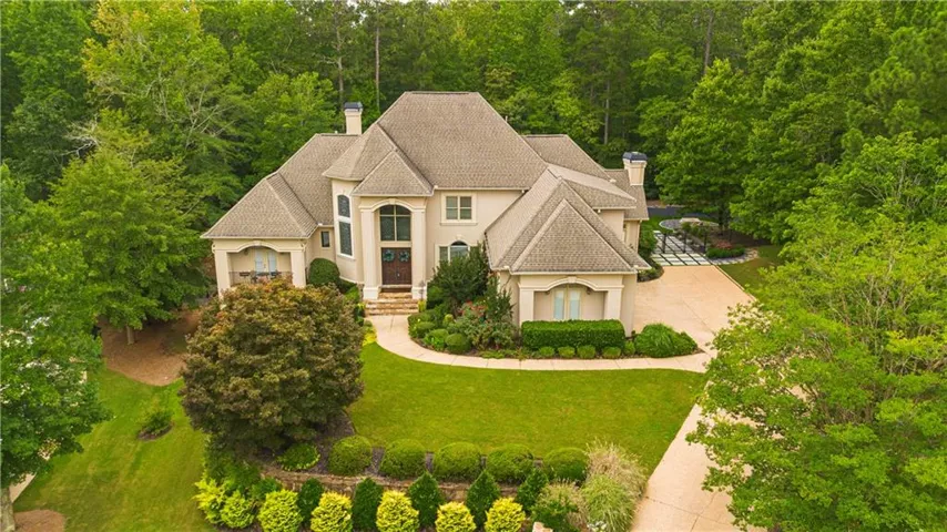 Stucco exterior residence with a multi-gabled roofline, arched window accents, and a prominent bay window feature