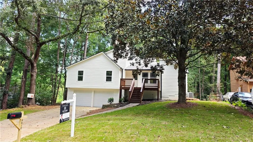 White siding exterior with a wood-finish deck and stairs