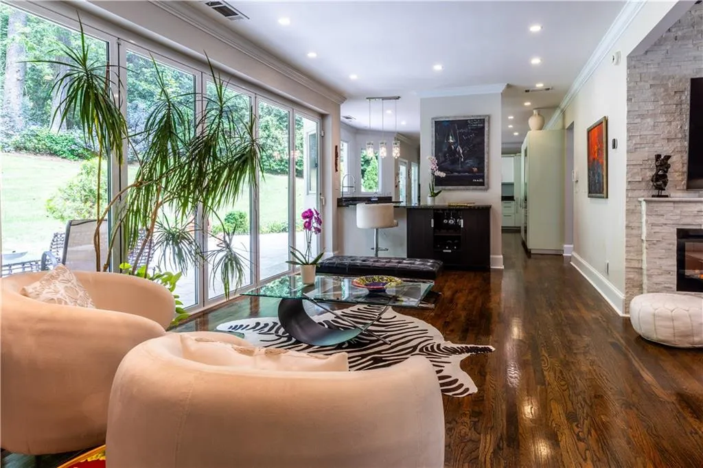 Living room with crown molding, wood finished floors, recessed lighting, and a stone fireplace