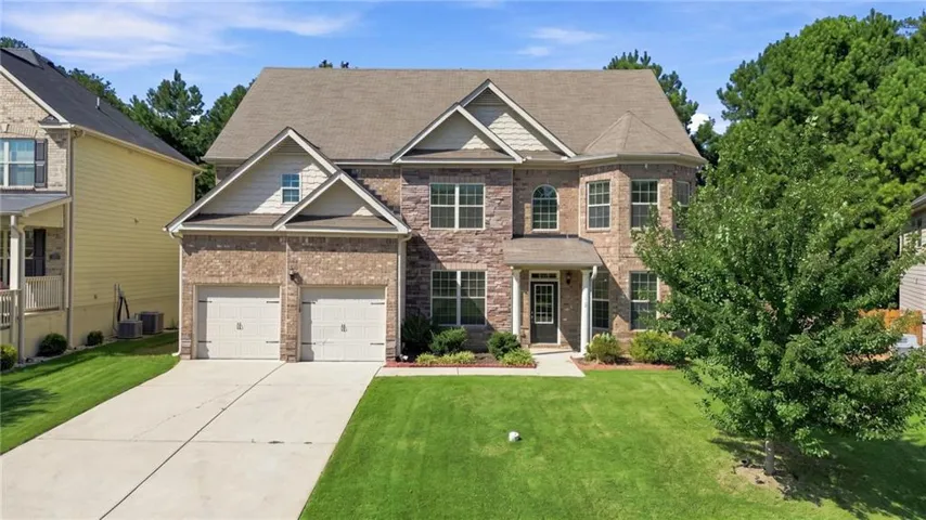 Two-story brick Colonial featuring a two-car garage, arched entryway with sidelights, and multi-pane windows