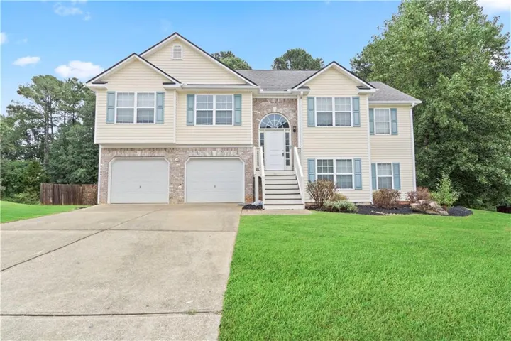 Split-level residence featuring a brick and siding exterior, an arched entry, a two-car garage, and a concrete driveway