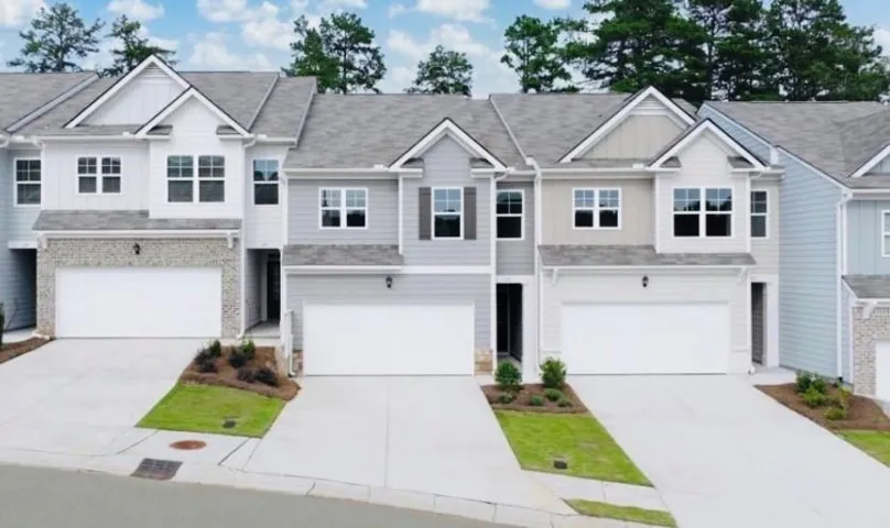 Contemporary townhome with a two-car garage, stone facade accents, and a grey shingle roof