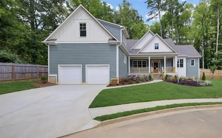 Craftsman-style exterior with a covered front porch, stone accents, two-car garage, and established landscaping