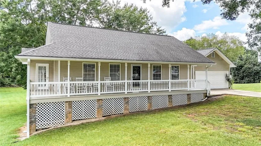 Ranch-style residence featuring a broad front porch with white railing, stone accents, and lattice skirting