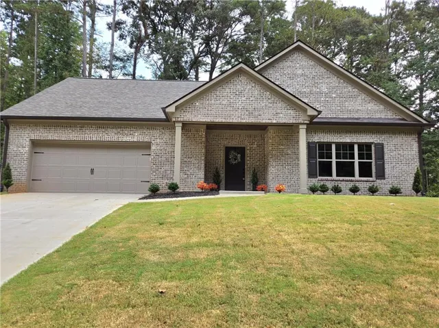 Brick exterior with a gabled roofline, columned entry, attached garage, and a concrete driveway
