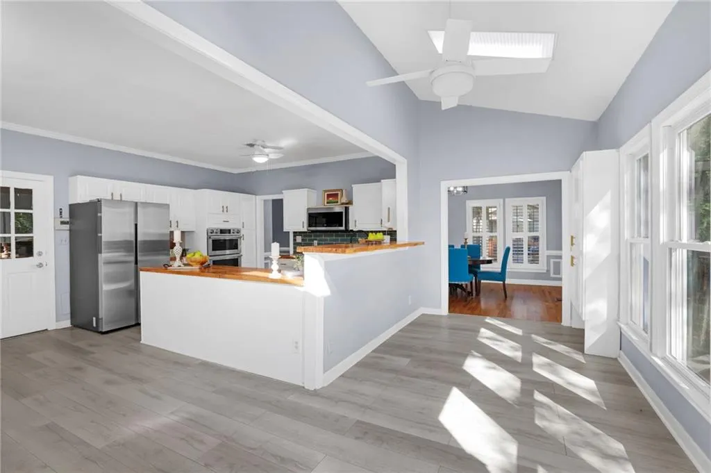 Kitchen featuring stainless steel appliances, white cabinets, wooden counters, kitchen peninsula, and light flooring