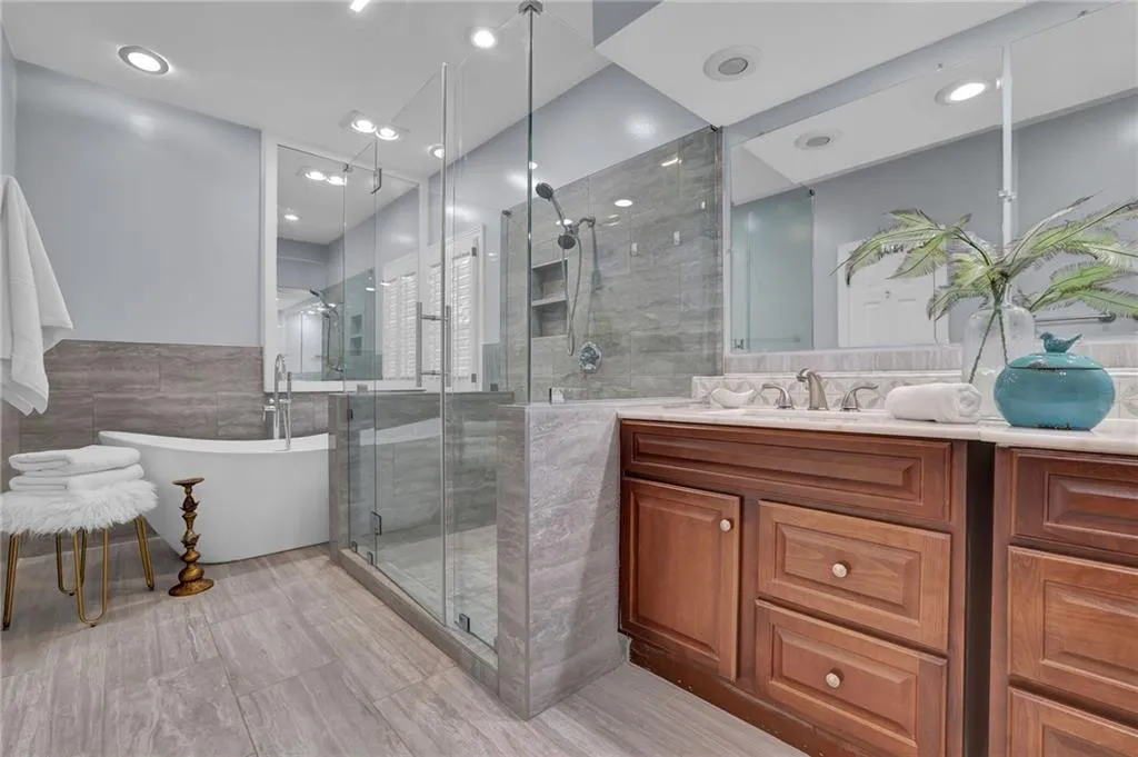 Bathroom with tile walls, vanity, and large shower and soaking tub