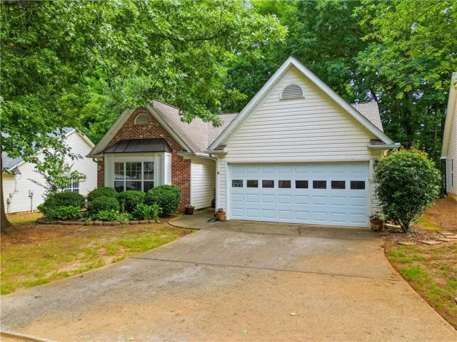 Traditional-style residence featuring a combination of brick and siding, a two-car garage, and a front bay window