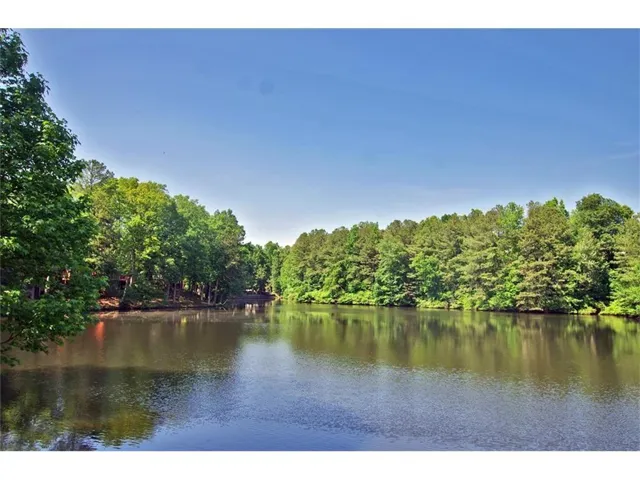 Waterfront setting featuring mature tree lines and clear blue skies
