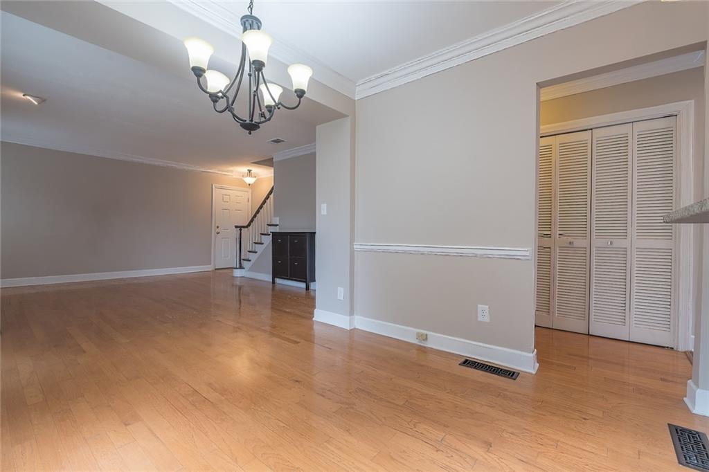 Unfurnished living room featuring ornamental molding, a chandelier, and light wood-type flooring