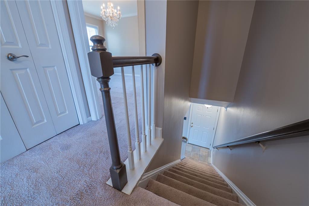 Staircase with an inviting chandelier, ornamental molding, and carpet