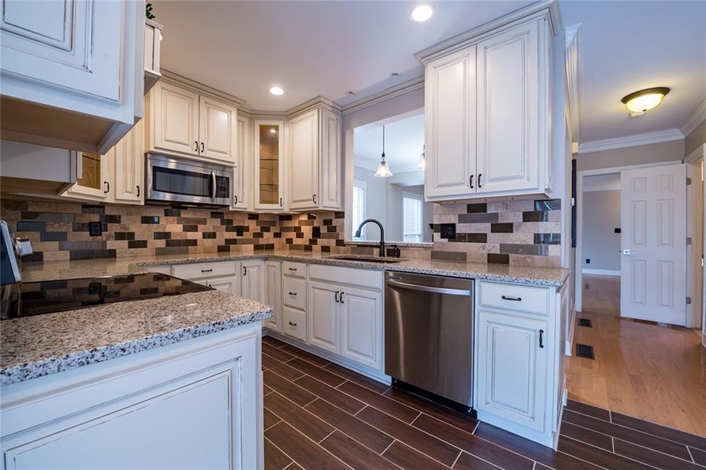 Kitchen with tasteful backsplash, dark hardwood / wood-style flooring, sink, appliances with stainless steel finishes, and ornamental molding