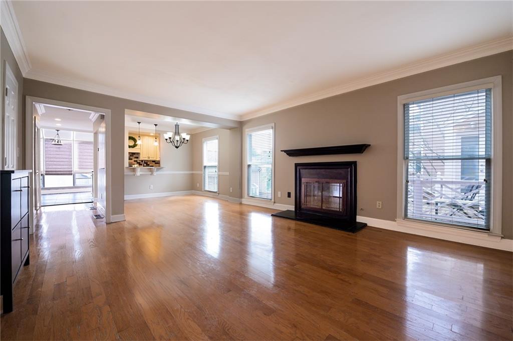 Unfurnished living room with crown molding, hardwood / wood-style floors, and a chandelier