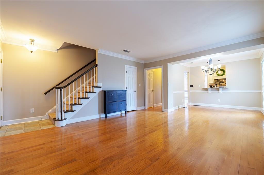Unfurnished living room featuring light hardwood / wood-style flooring, crown molding, and a chandelier