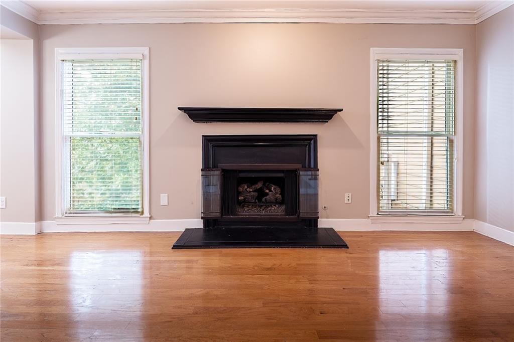 Unfurnished living room with light wood-type flooring, ornamental molding, and a wealth of natural light