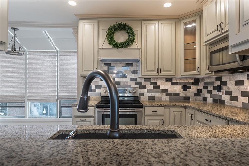 Kitchen with appliances with stainless steel finishes, backsplash, and light stone countertops