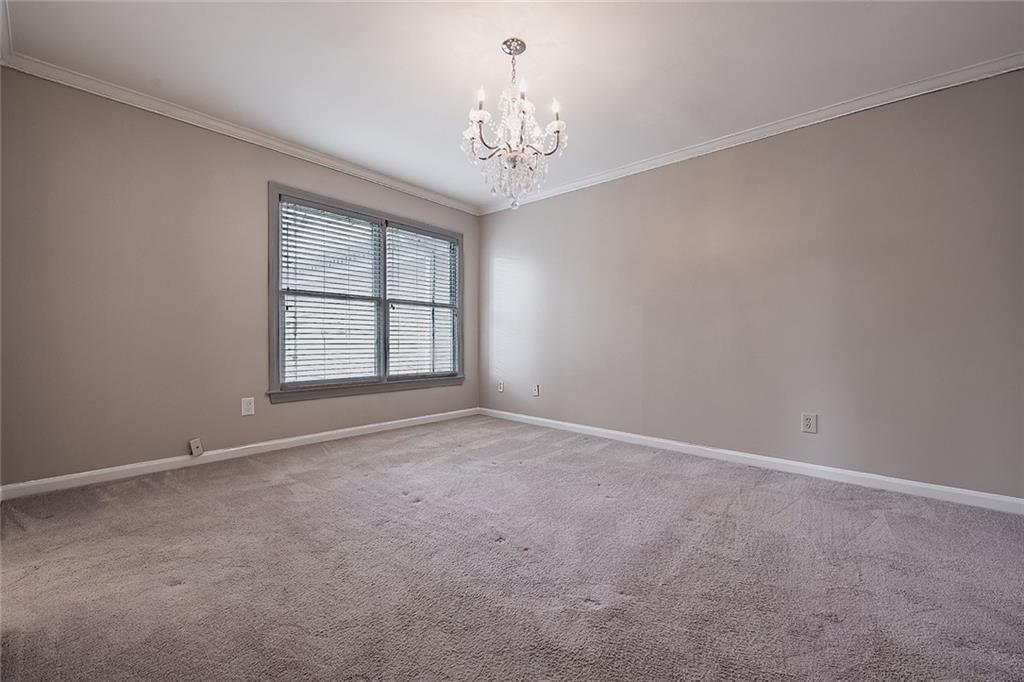 Carpeted empty room with an inviting chandelier and ornamental molding