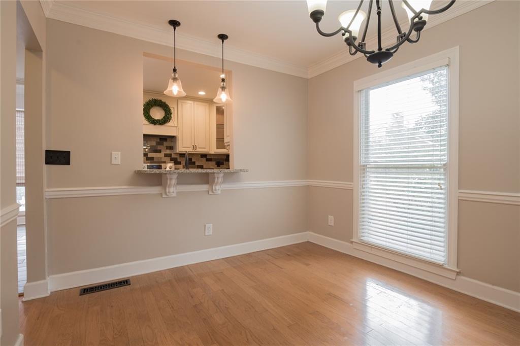 Unfurnished dining area featuring an inviting chandelier, light wood-type flooring, and crown molding