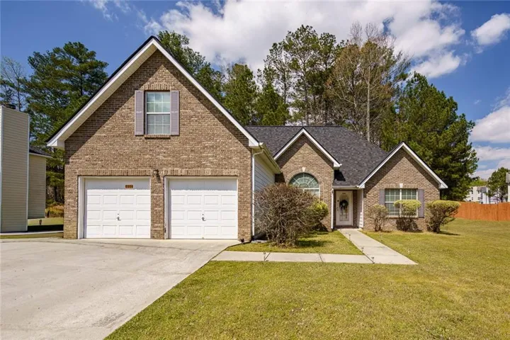 View of front facade with brick siding, concrete driveway, a garage, and a shingled roof