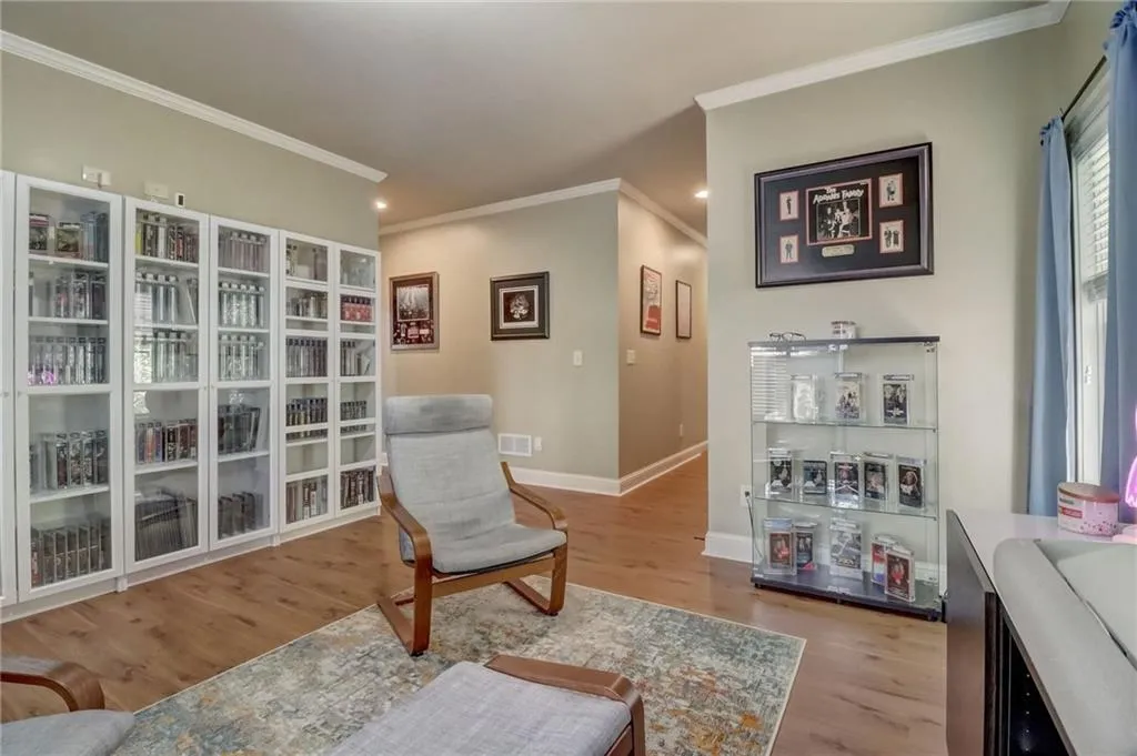 Living area with light hardwood / wood-style floors and crown molding