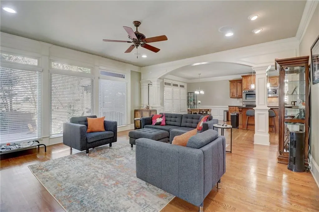 Living room with ceiling fan, light hardwood / wood-style flooring, ornamental molding, and ornate columns