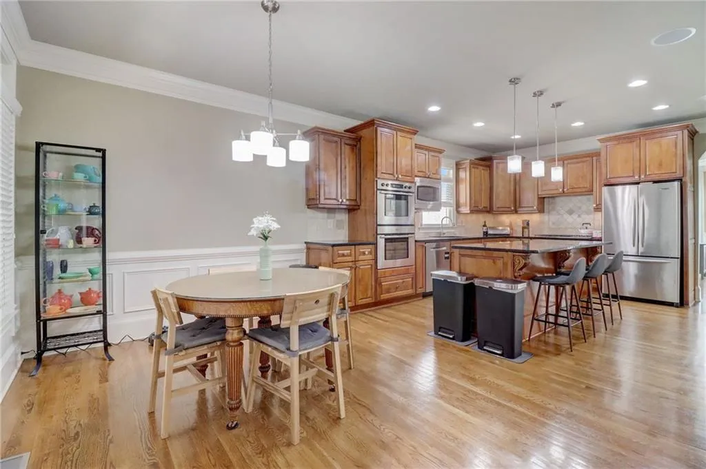 Kitchen featuring a center island, light wood-type flooring, stainless steel appliances, backsplash, and pendant lighting