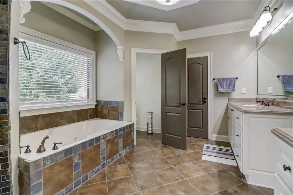Bathroom featuring tile floors, ornamental molding, tiled bath, and oversized vanity