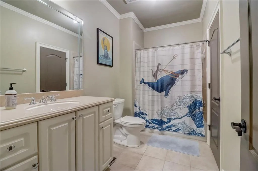 Bathroom with vanity with extensive cabinet space, tile flooring, toilet, and crown molding