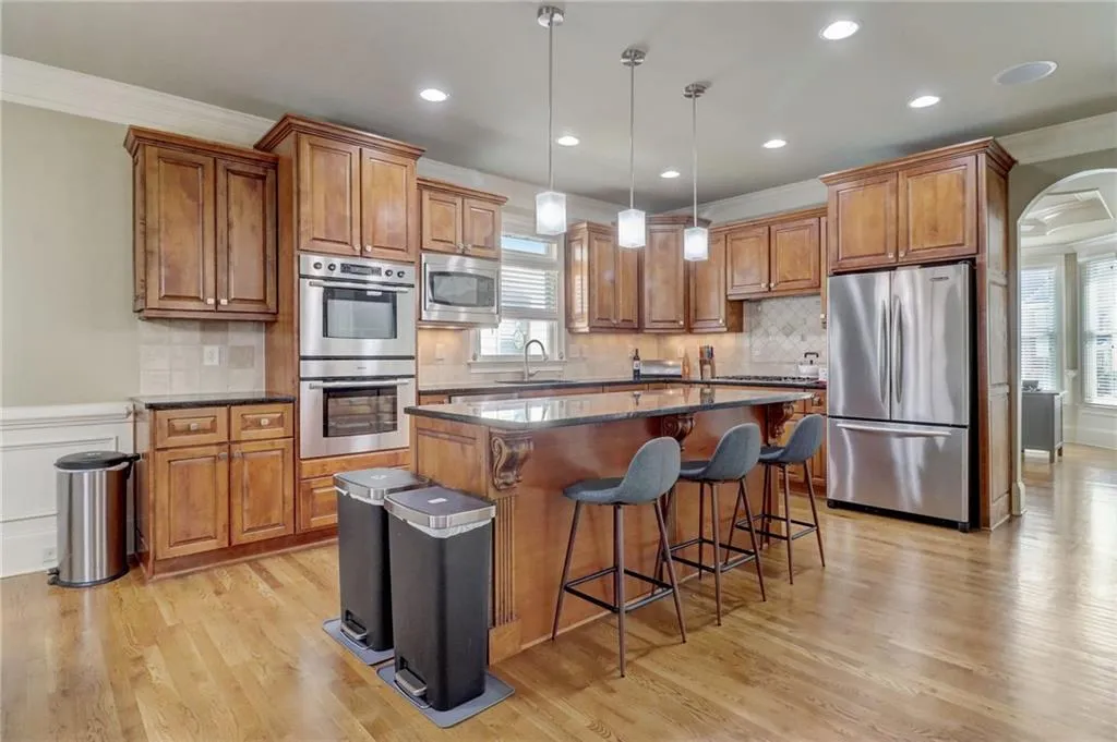 Kitchen with light hardwood / wood-style flooring, a kitchen island, tasteful backsplash, and appliances with stainless steel finishes