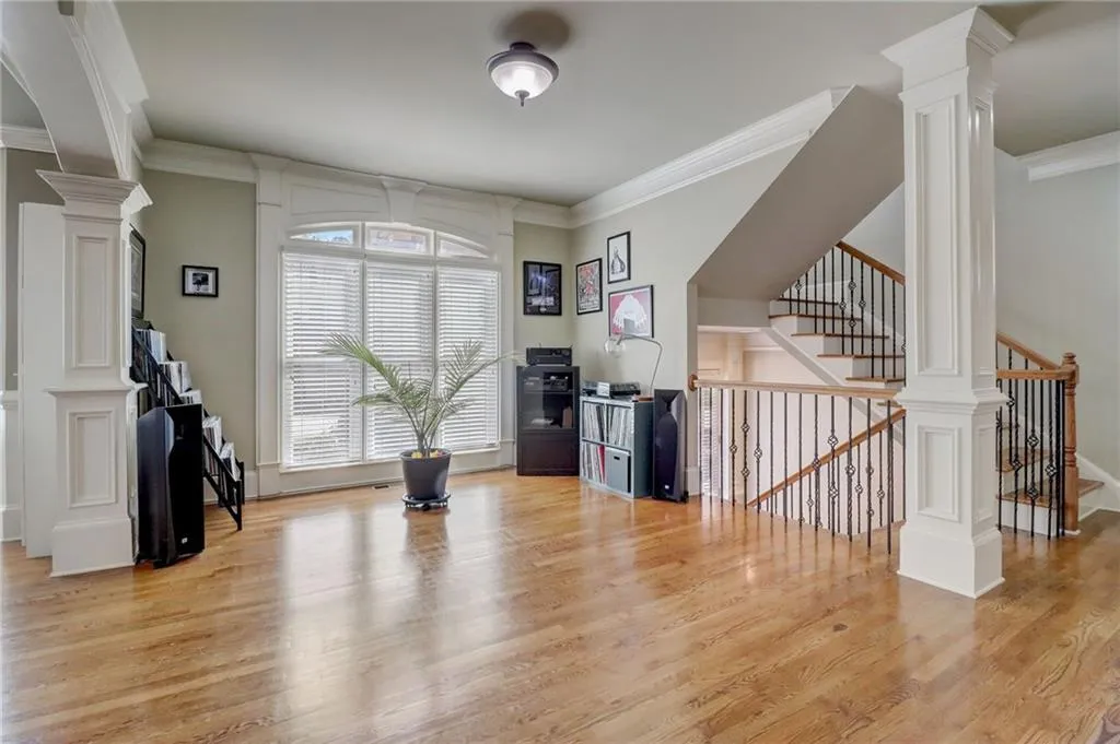 Exercise area featuring ornamental molding, decorative columns, and light wood-type flooring