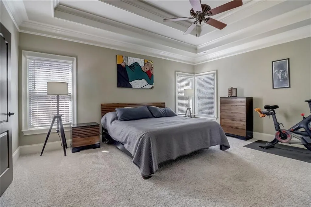 Bedroom with crown molding, ceiling fan, a raised ceiling, and carpet floors