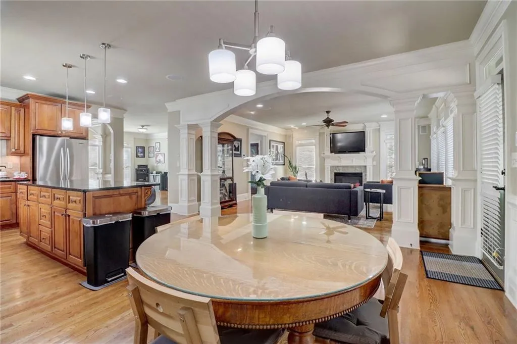 Dining area with ceiling fan, light hardwood / wood-style flooring, ornamental molding, and ornate columns